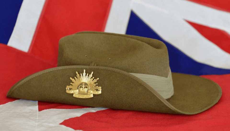 A green military-style hat featuring an Australian Defence Force badge, placed on an Australian flag symbolising military legal services and defence law expertise.
