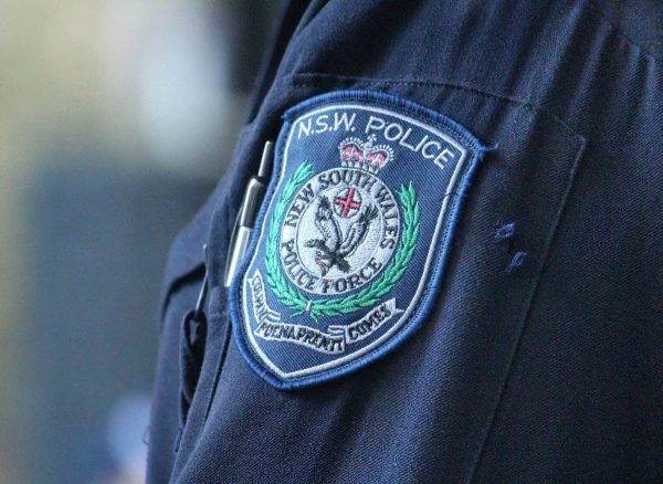 A close-up of a NSW Police officer’s uniform showing the badge with detailed insignia and embroidery, symbolizing law enforcement and community safety.