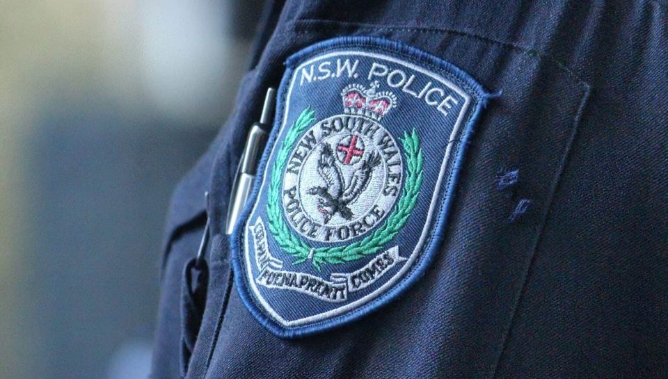Police NSW badge on uniform, law enforcement officer in official uniform, New South Wales police patch, legal authority, community service, law enforcement presence, public safety, official badge. A close-up of a NSW Police officer’s uniform showing the badge with detailed insignia and embroidery, symbolizing law enforcement and community safety.