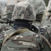 Military personnel in tactical camouflage uniforms, helmets, and gear, preparing for deployment, emphasizing security and defence services.
