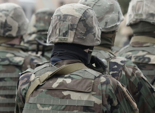 Military personnel in tactical camouflage uniforms, helmets, and gear, preparing for deployment, emphasizing security and defence services.