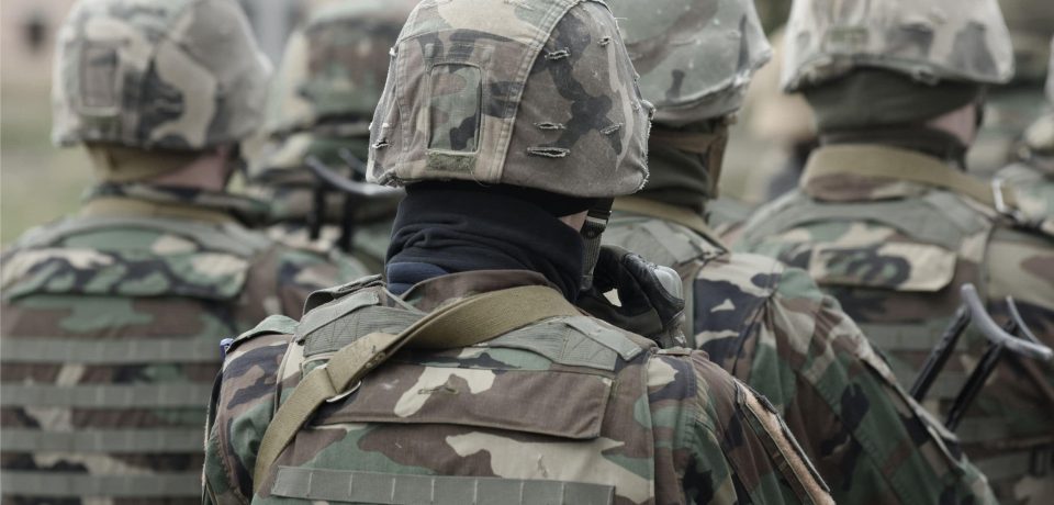 Military personnel in tactical camouflage uniforms, helmets, and gear, preparing for deployment, emphasizing security and defence services.