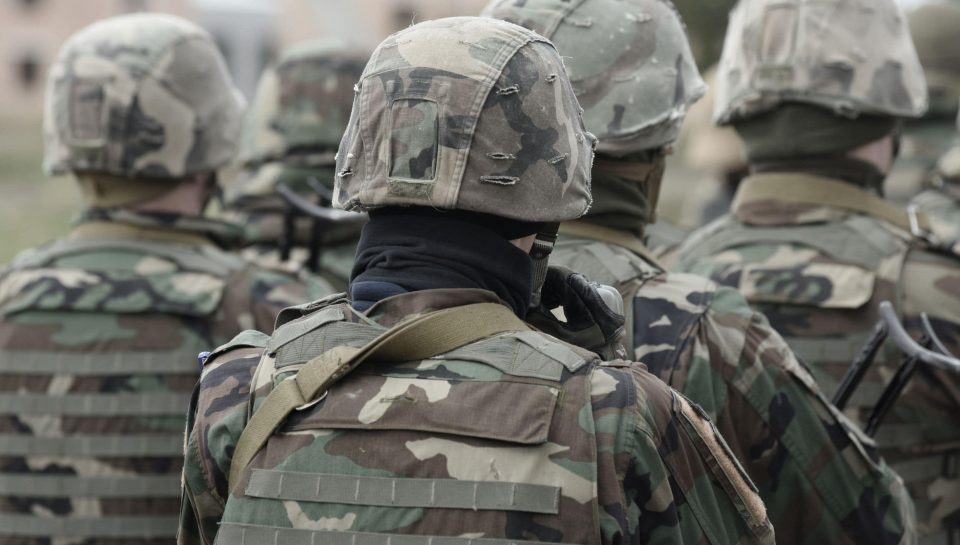 Military personnel in tactical camouflage uniforms, helmets, and gear, preparing for deployment, emphasizing security and defence services.