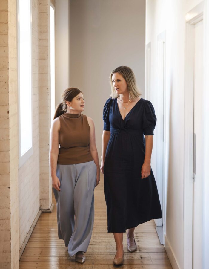 A professional woman and young girl having a serious conversation while walking in a modern office hallway, representing legal consultation and client support in Australia.