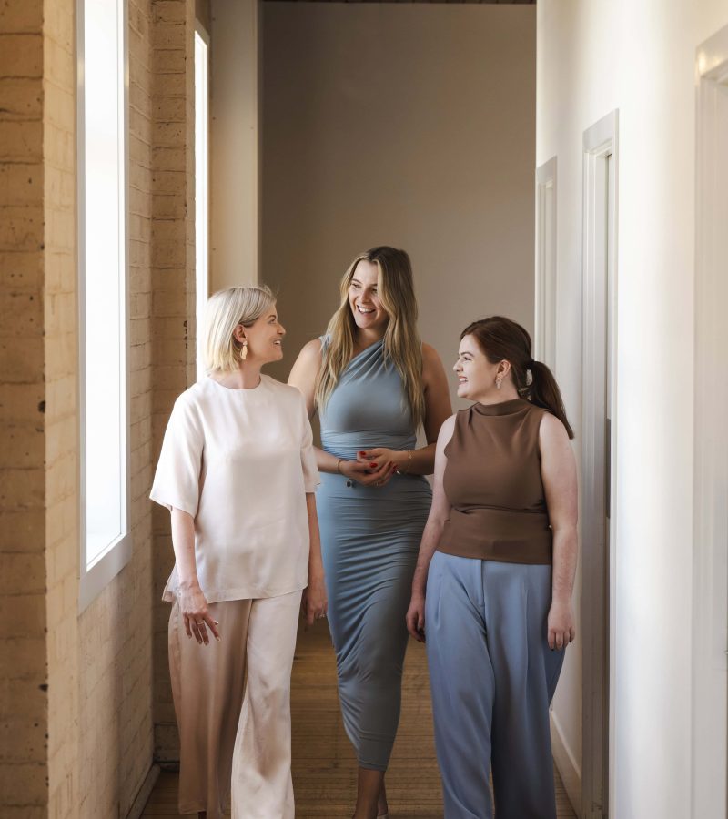 Professional women engaged in business conversation in an office corridor, representing trusted legal services and corporate law expertise.